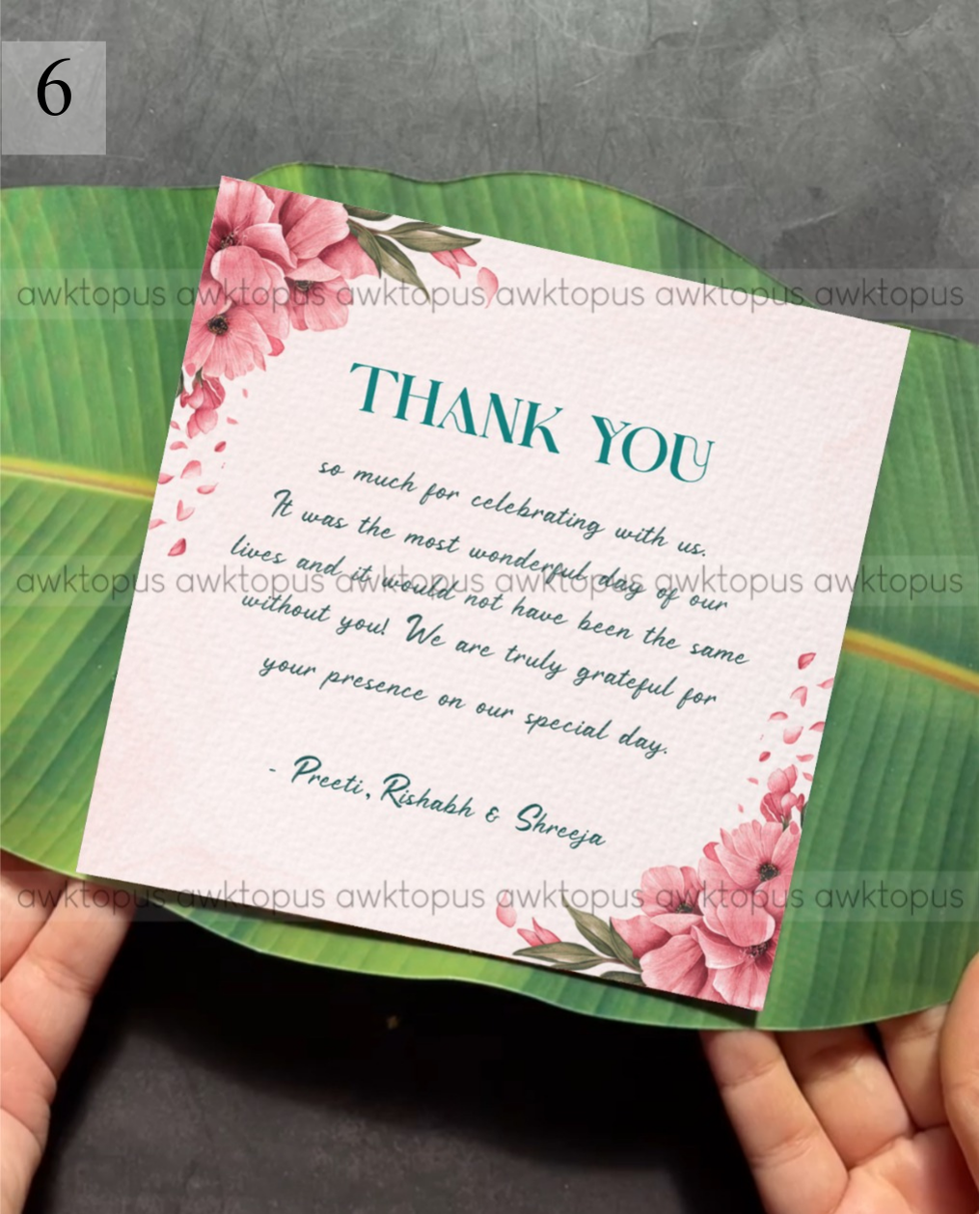 Floral thank you card held over a green leaf background